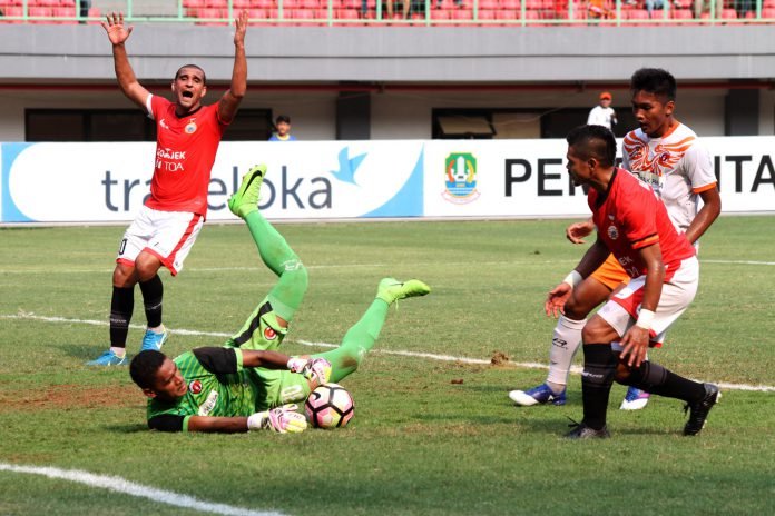 Penjaga gawang Perseru Serui, Hendra Mole (kiri) berusaha menahan bola dari pesepak bola Persija Jakarta, Bambang Pamungkas (kanan) pada pertandingan Gojek Traveloka Liga 1, di Stadion Patriot Candrabhaga, Bekasi, Jawa Barat, Selasa (19/9).