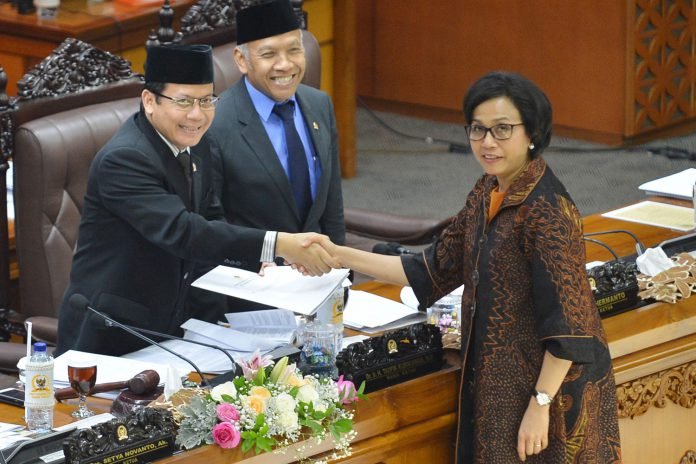 Menteri Keuangan Sri Mulyani (kanan) berjabat tangan dengan pimpinan rapat paripurna Taufik Kurniawan (kiri) disaksikan Wakil Ketua DPR Agus Hermanto saat menyerahkan laporan pandangan pemerintah saat Rapat Paripurna DPR ke-10 di Kompleks Parlemen, Senaya