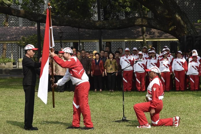 Presiden Joko Widodo (kiri) menyerahkan bendera Merah Putih kepada Ketua Kontingen Indonesia SEA Games XXIX Malaysia Aziz Syamsuddin (kedua kiri) saat upacara pelepasan di halaman Kompleks Istana Kepresidenan, Jakarta,