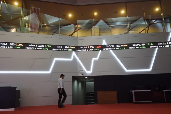 Seorang pria melintasi layar elektronik pergerakan saham di Bursa Efek Indonesia, Jakarta, Senin (30/10).